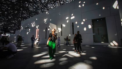 Una persona camina bajo las luces que atraviesan la cúpula del Louvre Abu Dhabi