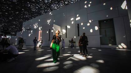 Una persona camina bajo las luces que atraviesan la cúpula del Louvre Abu Dhabi