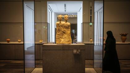 Una mujer junto a la "Estatua monumental con dos cabezas" de Jordania hacia el año 6500 a.C.