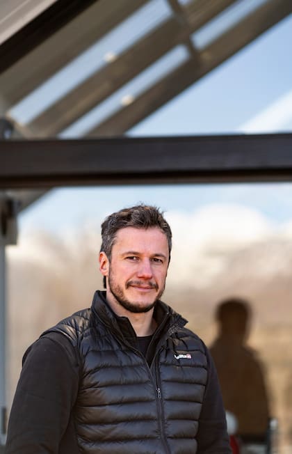 Matías, en el frente de su casa, que refleja las montañas