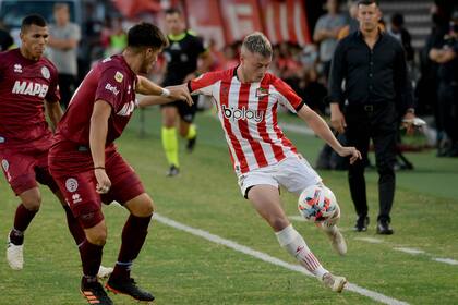 Matías Pellegrini es encerrado por la línea y Brian Aguirre; detrás, Jorge Almirón, el entrenador de Lanús.