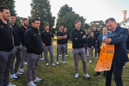 Mauricio Macri observa la camiseta que le entregó el director técnico Gonzalo Quesada, firmada por el plantel de Jaguares; observan, entre otros, Guido Petti Pagadizábal, Tomás Lavanini, Marcos Kremer, Agustín Creevy, Julián Montoya, Matías Moroni y el secretario de la Unión Argentina de Rugby, Fern