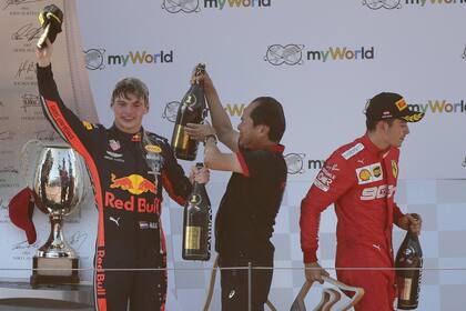 Max Verstappen celebra con Toyoharu Tanabe, director de Honda F.1, mientras Charles Leclerc abandona el podio; por el momento, la ceremonia de premiación está suspendida
