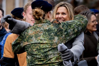 Máxima, con abrigo largo en tono gris, guantes y el gorro en la mano, abraza a su hija mayor, en un gesto efusivo y fuera de protocolo