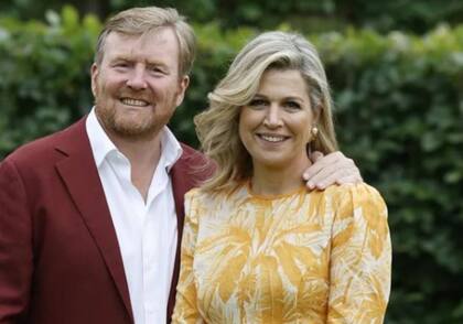 Máxima con un vestido veraniego y el rey con un osado saco bordó