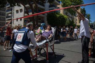 Médicos israelíes evacuan a una mujer de un vecindario residencial donde un cohete disparado desde la Franja de Gaza golpeó el área, en Ramat Gan, en el centro de Israel, el sábado 15 de mayo de 2021.