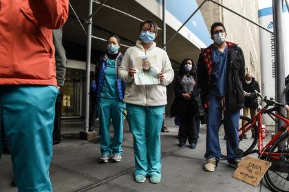 Médicos y enfermeros del hospital Mount Sinai muestran fotos de sus colegas fallecidos y ruegan que les envíen más suministros para protegerse