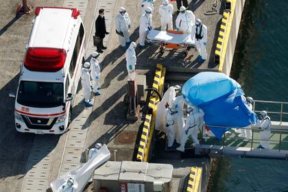 Médicos y oficiales japoneses trasladan a una persona que viajaba a bordo del Diamond Princess, en el puerto de Yokohama