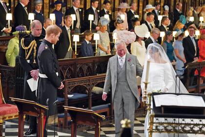 Meghan Markle camina hacia el altar acompañada del entonces príncipe Carlos (hoy rey); Harry espera por ella