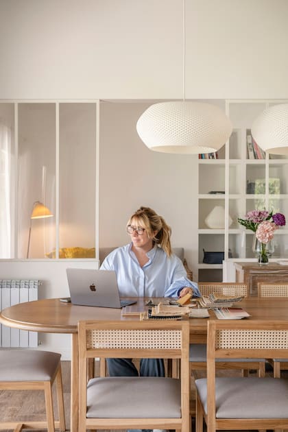 Melina Trogolo sentada en la mesa de comedor para la que eligieron sillas con el clásico esterillado provenzal, pero de diseño actualizado.