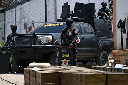 Miembros del Grupo Antiextorsión y Secuestro (CONAS) hacen guardia mientras se exhiben armas, municiones y motos confiscadas durante una conferencia de prensa después de que las autoridades tomaron el control de la prisión en Tocorón, estado Aragua, Venezuela, el 21 de septiembre de 2023