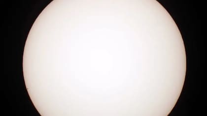Mercurio es realmente pequeño comparado a otros planetas. Aquí se le ve como un puntito a la izquierda, mientras atraviesa frente a la cara del Sol