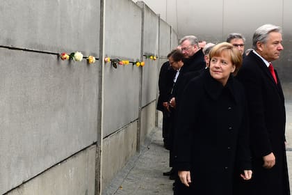 Merkel y el alcalde de Berlín, Klaus Wowereit, se van después de poner rosas en un segmento preservado del Muro de Berlín durante las conmemoraciones del 25 aniversario de la caída, en Bernauer Strasse