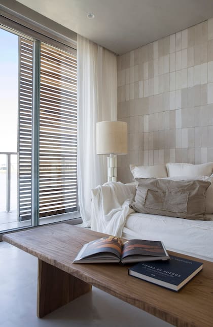 Mesa baja (Estudio Trae), sillón con funda, almohadones y manta (Casa Tarlo), lámpara de mesa (Duveen Deco). Pared revestida con ladrillos refractarios de cemento.