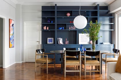 Mesa con tapa de granito ‘Black Cosmic’ con tratamiento leather y sillas con respaldo laqueado y tapizado de cuero (Bull). Lámpara colgante (Iluminación Agüero).