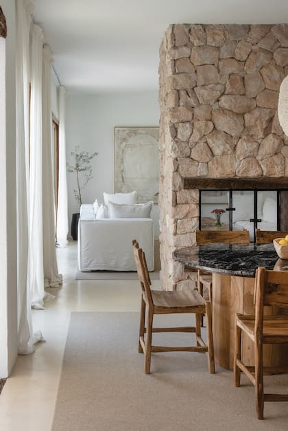 Mesa con tapa de granito ‘Boreal’ y base de petiribí y sillas de laurel hechas con piezas encastradas (Lau Interiors).