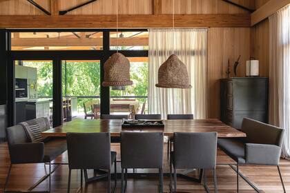 Mesa con tapa de madera maciza y patas metálicas esmaltadas y sillas ‘Baru’ con y sin apoyabrazos (todo de Solsken), estas últimas distinguidas en 2020 con el Sello de Buen Diseño Argentino. En el extremo de la galería asoma la parrilla.