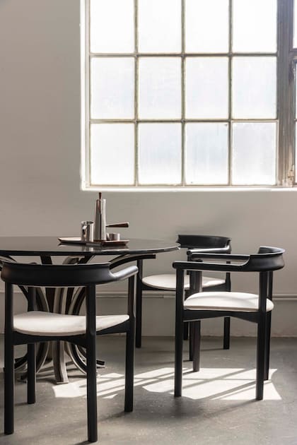 Mesa de aluminio y mármol negro del arquitecto Nijelson, sillas de madera laqueada negro de Alberto Churba.