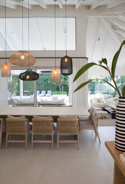 Mesa de comedor con base de madera maciza y tapa de Caesarstone y sillas con respaldo de cordón de papel (Estudio Mariana Flombaum). Lámparas colgantes ‘Kute’ (Atmosphère d’Ailleurs).