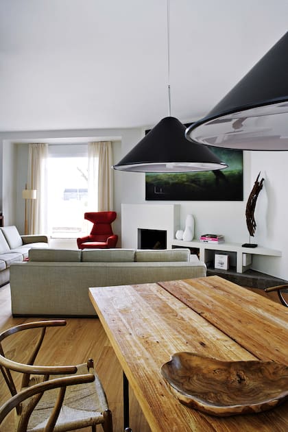 Mesa de comedor de tablones rústicos de teca con base de metal y juego de sillas ‘Ch24’, diseño original de Hans J. Wegner. Lámparas colgantes (Tom Dixon).