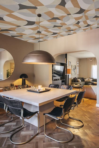 Mesa de comedor en cemento color caju (Mezcla). Sillas Scava con asiento de cuero y pie de bronce (Ai Haus). Lámpara Fungi Black (De Arcos). Empapelado retro (Sophie Empapelados).