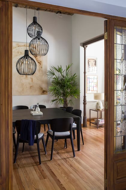 Mesa de comedor en paraíso de poro abierto, sillas ‘Hips’ de guatambú con tapizado antimancha y tres lámparas ‘Balun’ de hierro (todo de Salazar Casa). Obra de arte de Franco Cuttica.