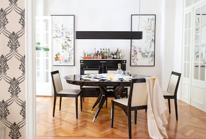 Mesa de comedor heredada y lámpara de La Feliz. “Hice estas pinturas para honrar la altura de los techos”, die Rosario sobre las que flanquean el bar.