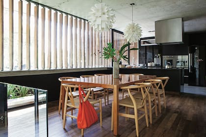 Mesa de comedor (Santorini) con arreglo (Flores One Way), sillas ‘Wishbone’ (CDI) y lámparas ‘Artichoke’, de Louis Poulsen. Heladera Whirlpool engamada con la mesada de granito negro