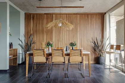 Mesa de laurel con tapa entelada en lino laqueado y sillas de hierro y cuero (Las Marinas). Piso y revestimiento de pared (Patagonia Flooring).