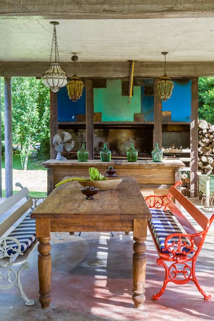 Mesa de madera maciza con bancos ‘Bancoooo’ (Estudio IK). Similar al de la cocina, piso de cemento alisado con formas y colores (Pablo Hernán Cortes).