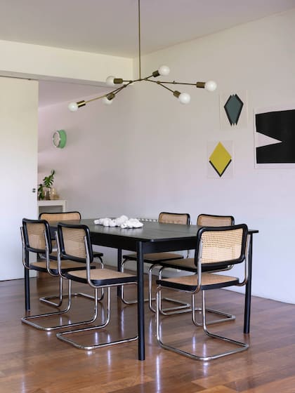 Mesa de madera negra (Estudio Te). Sillas ‘Cesca’ (Thonet). Lámpara de bronce (Estudio Molé). Cerámicas (Cecilia Nigro). Obras colgadas en la pared (Monocopia).