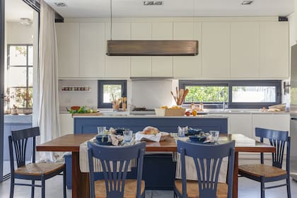 Mesa de timbó (Mesopotamia) con caminos, individuales y servilletas de Lado Blanco Home y vajilla de Salazar Casa. as pintaron de azul. Lámpara colgante ‘Grisín’, en bronce (La Feliz).