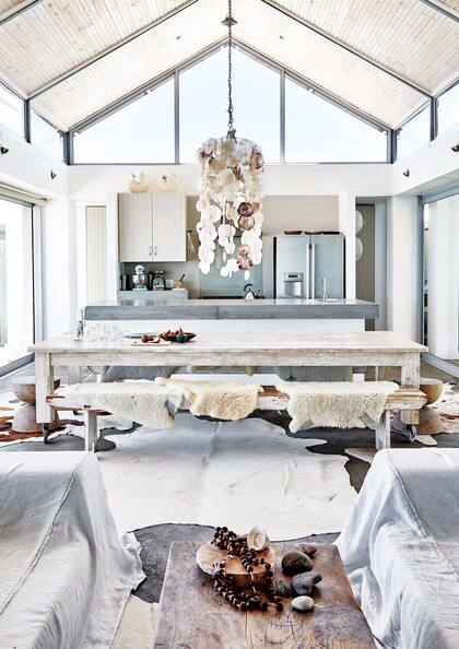 Mesa ratona de madera recuperada y lámpara colgante hecha por Caroline con caracoles que encontró en la playa.