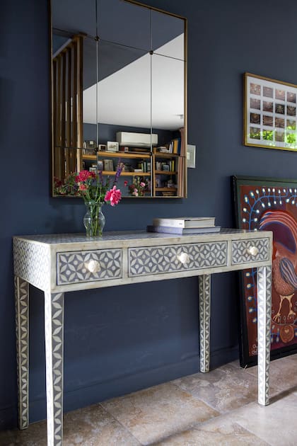 Mesa recibidora de nácar (Landmark) y espejo realizado a medida. Para la elección de la paleta de colores, optó por un gris azulado para las paredes que conversa con los textiles en neutro y algunos toques de color.