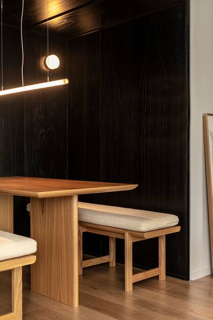Mesa y bancos de roble americano (Alejandra Nusenovich) con colchonetas, lámpara de techo y aplique (Huup). El piso interior es vinílico símil madera (Patagonia Flooring).