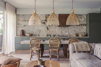 Mesada, alzada y mesa/isla en granito ‘Alpinus’ (Canteras del Mundo) trabajado por Marmolería Ragomar. Campana con acabado óxido (Compañía Nativa Estudio). Muebles de cocina en melamina ‘Safari’ de Faplac.