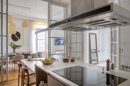 Mesada de cuarzo Purastone (Rocha y Cia.) y campana (Cooking Solutions). Mesa de comedor diario con sillas ‘Moller’ en petiribí, bajomesada y alacenas con puertas en MDF laqueado (todo de Aserrín Hace Ran).