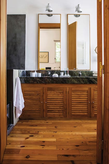 Mesada de mármol ‘Verde Bosque’ con doble bacha y lámparas amuradas sobre los espejos. Foto: Santiago Ciuffo