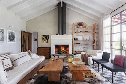 Mesas bajas (Monogiraud). Alfombras de cuero de vaca y de telar (Elementos Argentinos). Junto a la chimenea, cuadro de Eduardo Hoffmann. Sillones con funda y almohadones (Malena Ana).