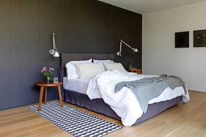 Mesas de luz, cama con funda (ambas, Estudio LDMB) y acolchado en lino natural (Gutiérrez Deco). Alfombra vinílica ‘Gittan’ (Brita Sweden), dúo de lámparas ‘Tolomeo Parete’ en aluminio pulido (Artemide) y cuadros de Mauro Bernardini.