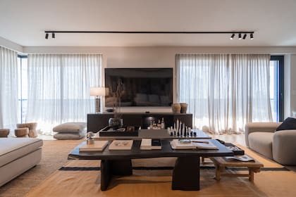 Mesas ratonas diseñadas a medida por el estudio: la de acero fue realizada por Artefacto; la de madera negra, por El Mueble SRL, La bajita en sentido perpendicular es de Area Design (Uruguay). Cortinas de Gasa Hunter Douglas por Luzzi Disegno