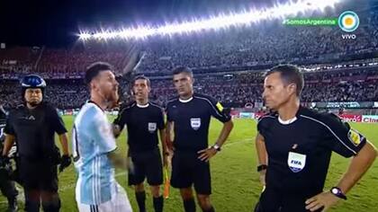 Messi con la terna arbitral del partido entre la Argentina y Chile en el Monumental