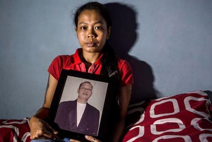 Una mujer en Indonesia con la foto de su marido que murió tras beber alcohol ilegal, conocido localmente como "oplosan".
