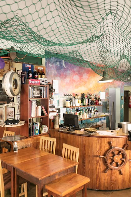 Mezcla de bodegón tradicional y cantina moderna, el salón está decorado con redes que cuelgan, timones de madera, balanzas y carteles viejos.