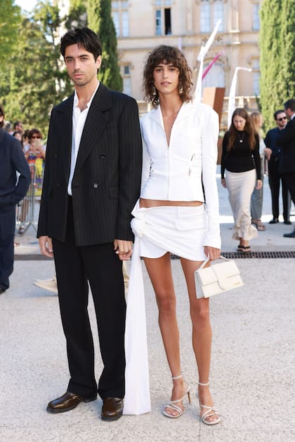 Mica Argañaraz con el director de cine y artista Mitch Ryan. La top argentina lució un blazer y una minifalda tipo pareo y Le Grand Bambino, la cartera icónica de Jacquemus.