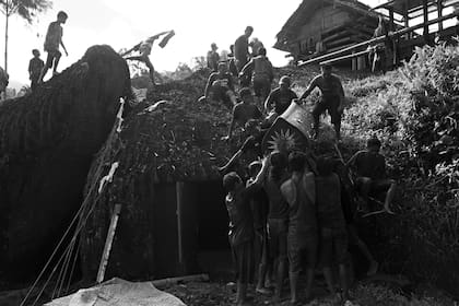 Miembros de la familia llevan el ataúd que contiene el cuerpo de Naomi Malino a la tumba en una roca durante el ritual de entierro o ceremonia de Rambu Solo en su honor en el pueblo de Lempo.