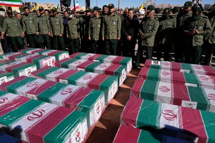 Miembros de la Guardia Revolucionaria de Irán, junto a ataúdes, cubiertos con la bandera nacional, de las víctimas de un doble atentado, durante su funeral, en la ciudad de Kerman, el 5 de enero de 2024. (AP Foto/Vahid Salemi)
