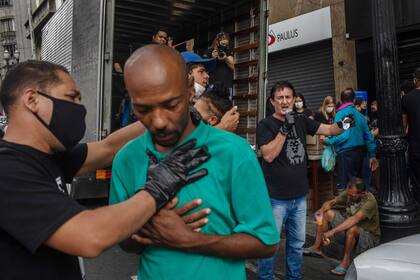 Miembros de la iglesia evangélica Frutos do Senhor hace bautismos mientras ofrecen el desayuno en una calle del centro de San Pablo
