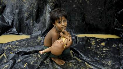 Un refugiado Rohingya de Myanmar sostiene un bebé después de llegar a un campo de refugiados cerca de la ciudad de Teknaf, Bangladesh