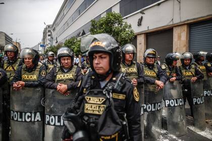 Miembros de la policía vigilan a manifestantes, simpatizantes del presidente de Perú Pedro Castillo, celebrando la noticia del cierre del Congreso